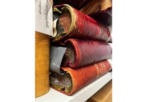 A stack of old, worn leather covered books with marbled pages