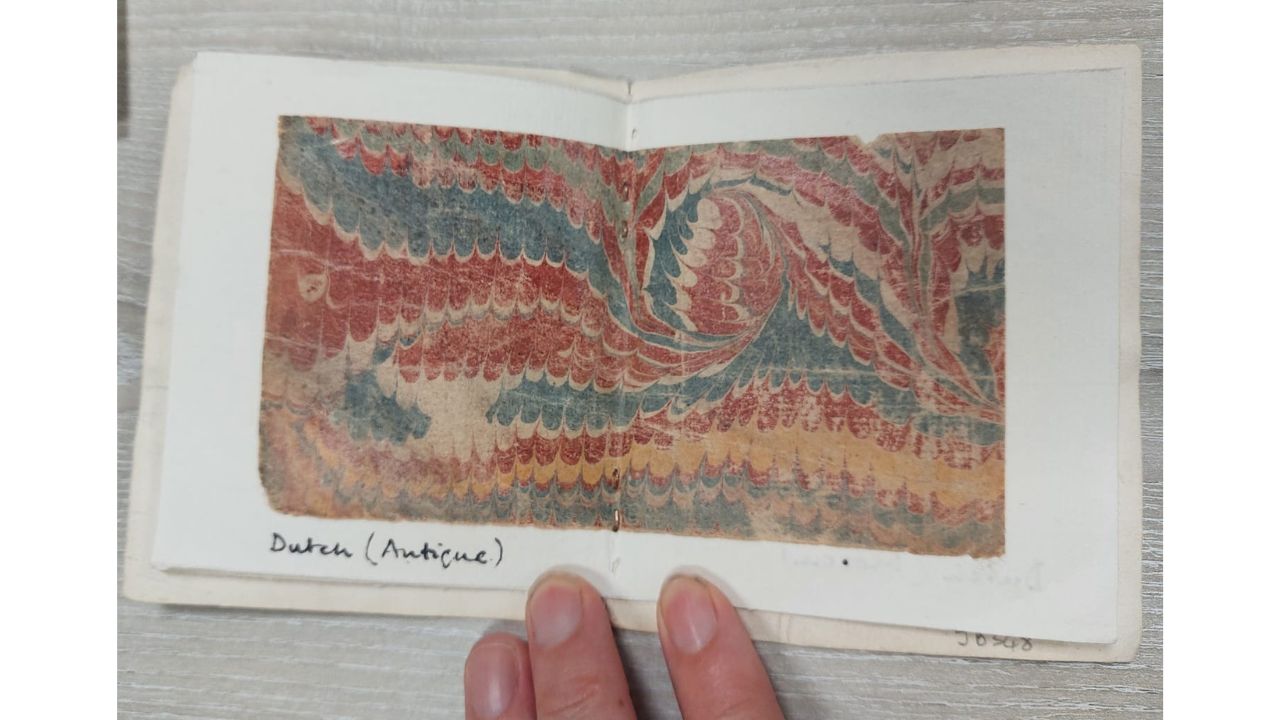 A handstitched book showing examples of marbled book end papers. Dutch Antique