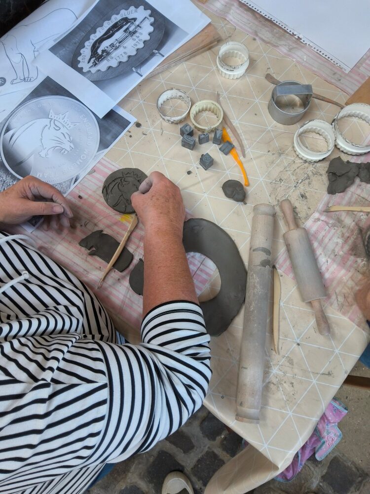 Overhead view of person engraving a roaring lion's head onto a clay disc