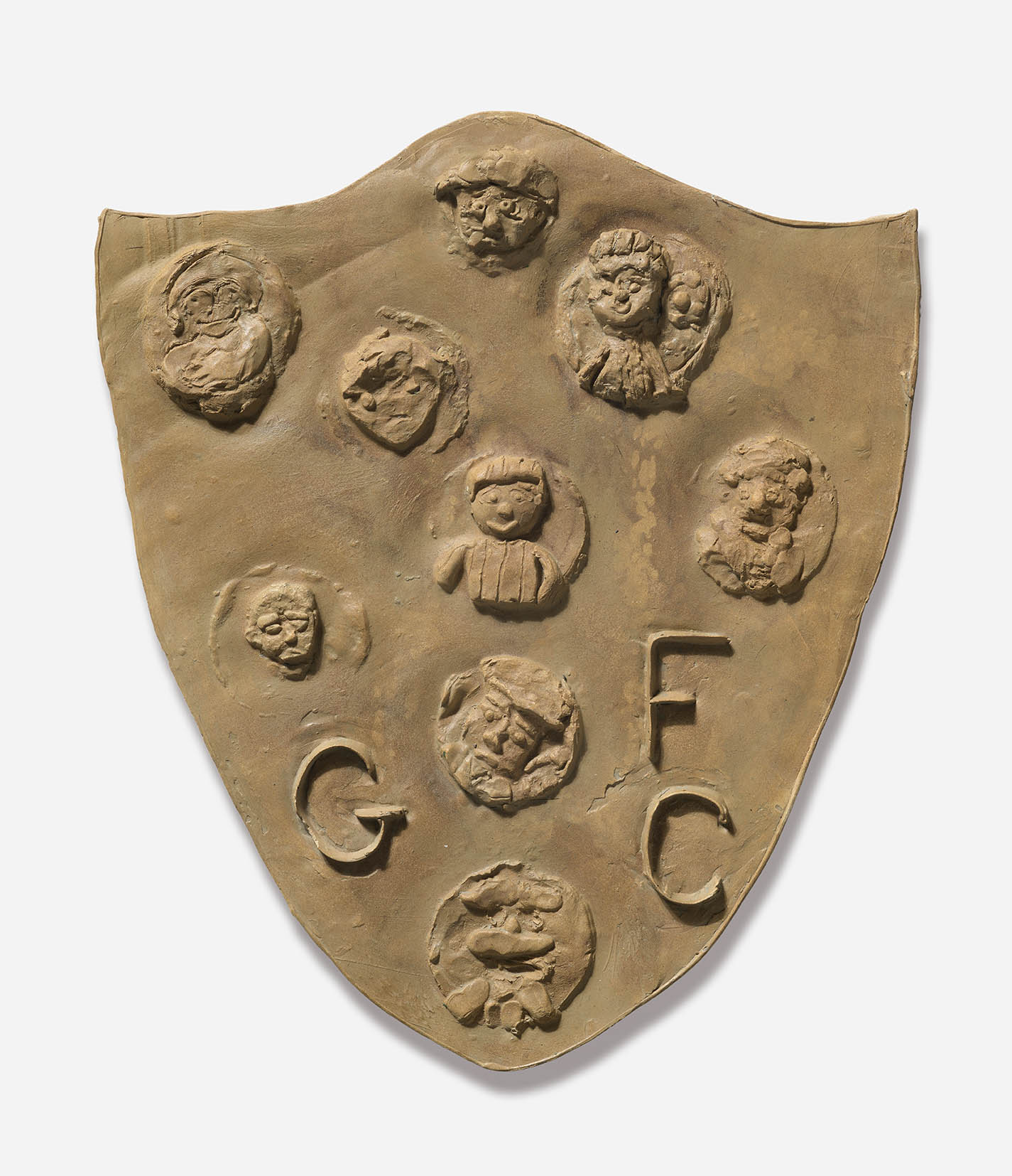 A plaster shield, with 9 individual discs each bearing a different face and the letters GFC