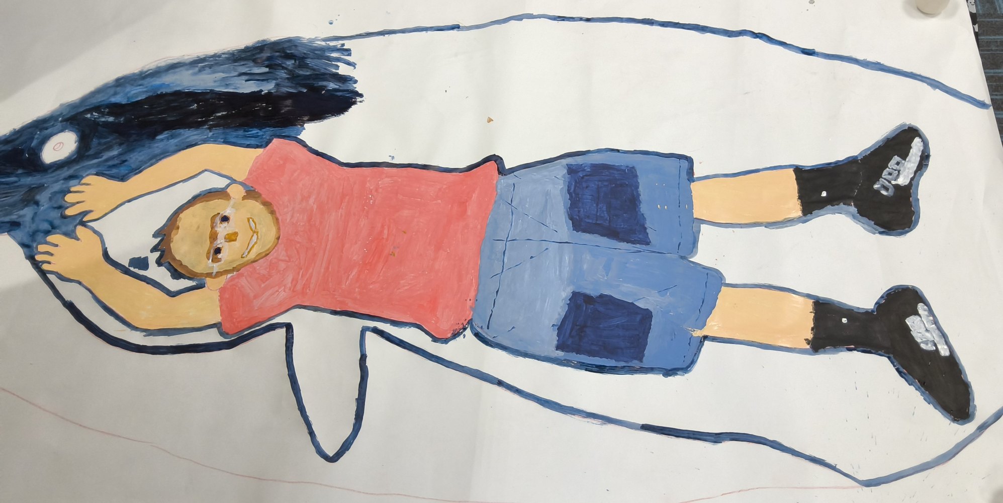 A full sized figure with red top, blue shorts and black socks and shoes, is drawn inside a blue whale