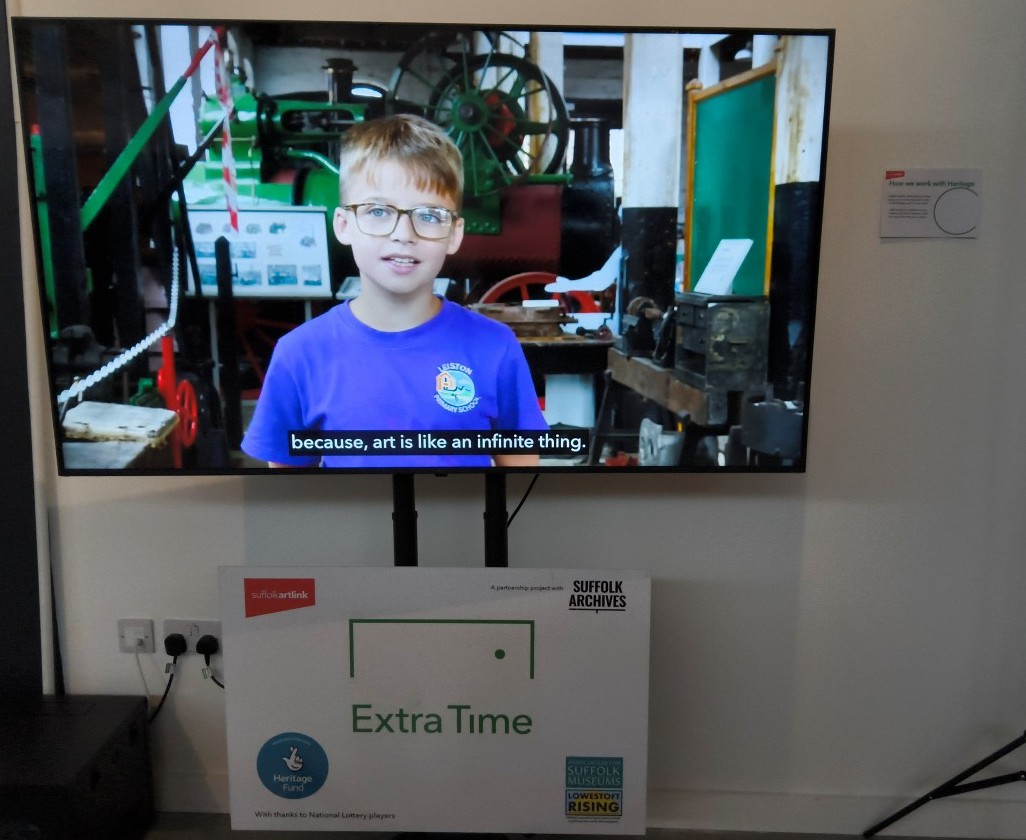 A large TV screen showing a child in the foreground and behind him a large steam engine. The caption reads ... because art in like an infinite thing.