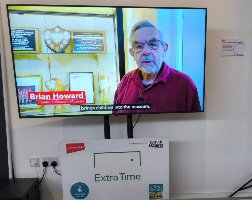 A large TV screen with a gentleman - Brian Howard - and a caption saying ...brings children into the musem