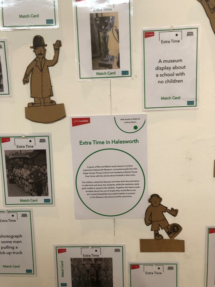 A white display panel with information sheets, photographs and cardboard cut out football figures