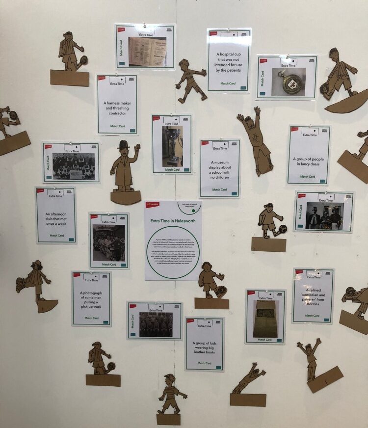 A white panel with cardboard cut out figures of footballers, photographs and ainformation sheet