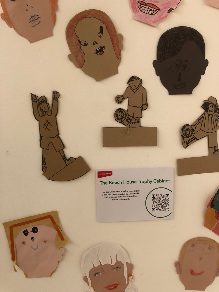 The Beech House Trophy Cabinet - with a QR code so that visitors can listen to the poem on their phones, surrounded by football figures and faces