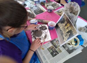Pupil making clay face of footballer