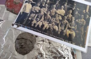 Clay face next to photo of football team
