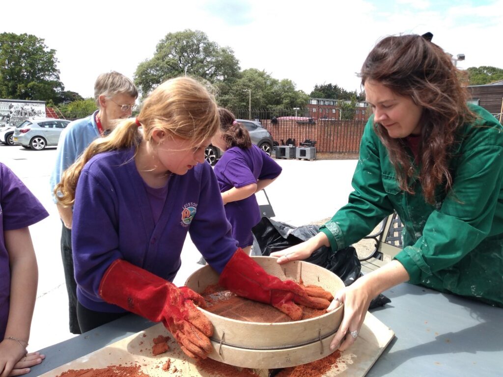Pupil sifting sand into the mould