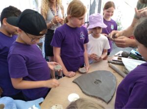 Pupils looking at a shield with a clay disc impression
