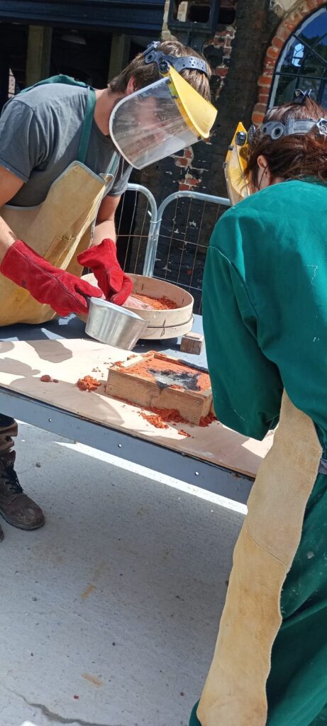 Sam and Ellie pouring melted pewter into the mould.
