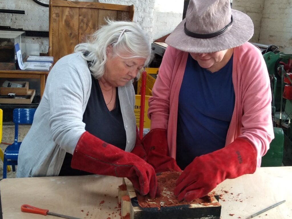 Participants wearing huge ’oven’ gloves, turning out the pewter model.