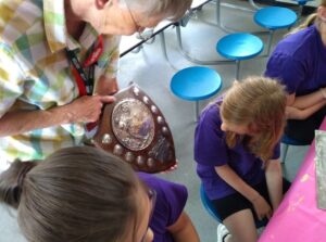 Volunteer and pupils talking about a shield