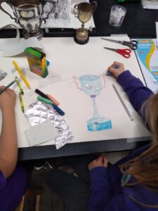 Pupil drawing a clue pencil and collage trophy