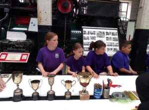 4 pupils looking at 4 sorting trophies in the Long Shop
