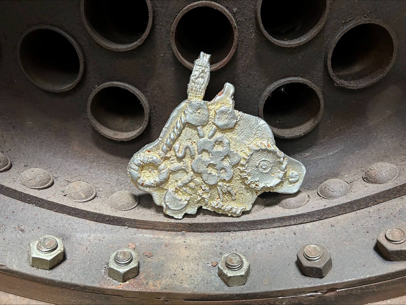 A model cast in pewter, using engineering marks and motifs and positioned inside a large metal space with bolts and rivets