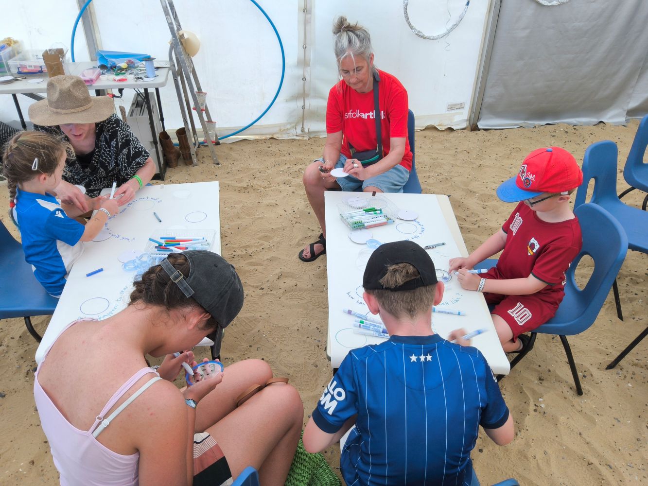 A group of adults and children seated around tables and drawing