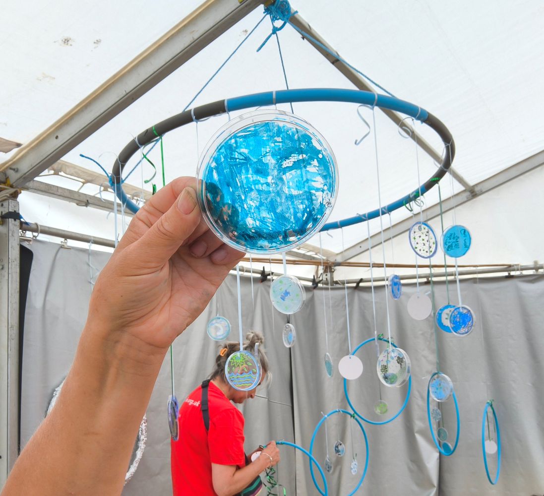 A bright blue disc, suspended from a hoop with other hoops and discs in the background
