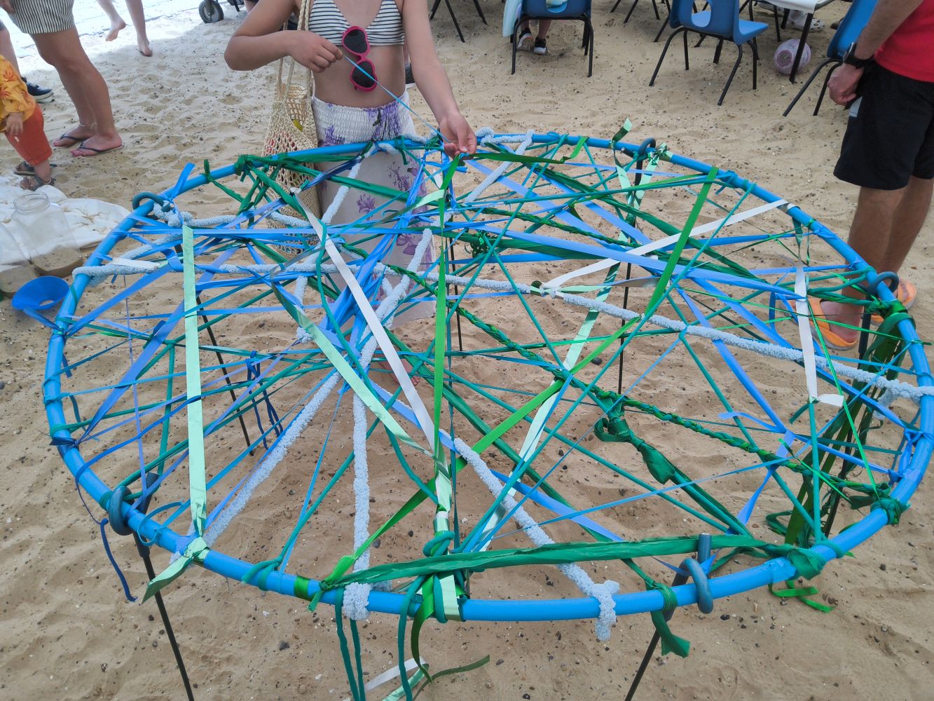A large blue hoop with coloured ribbons woven across it