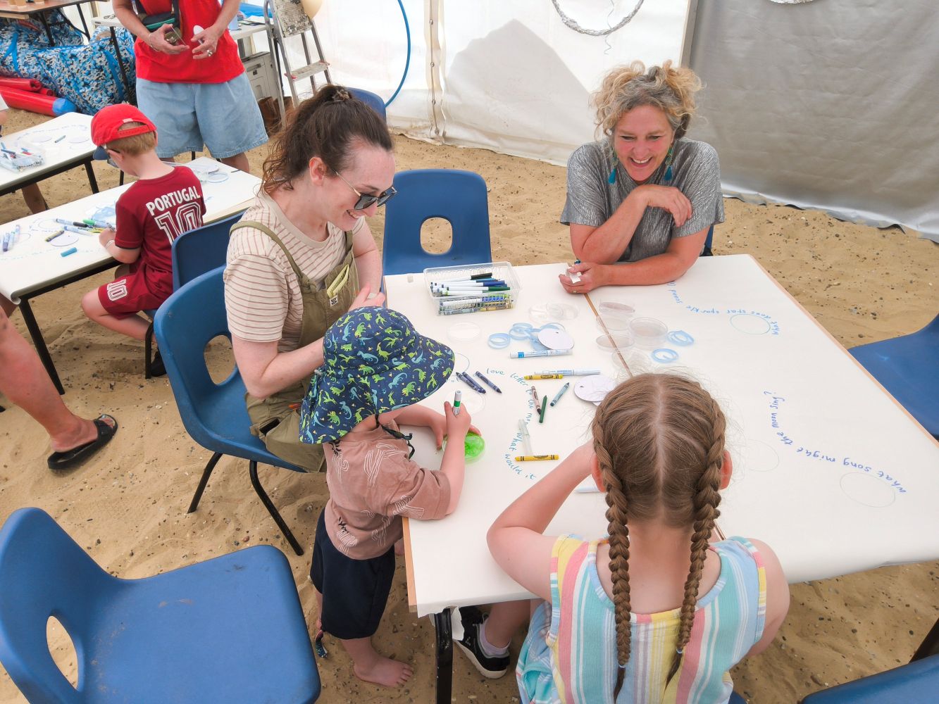 A group of adults and children seated at a table drawing moons