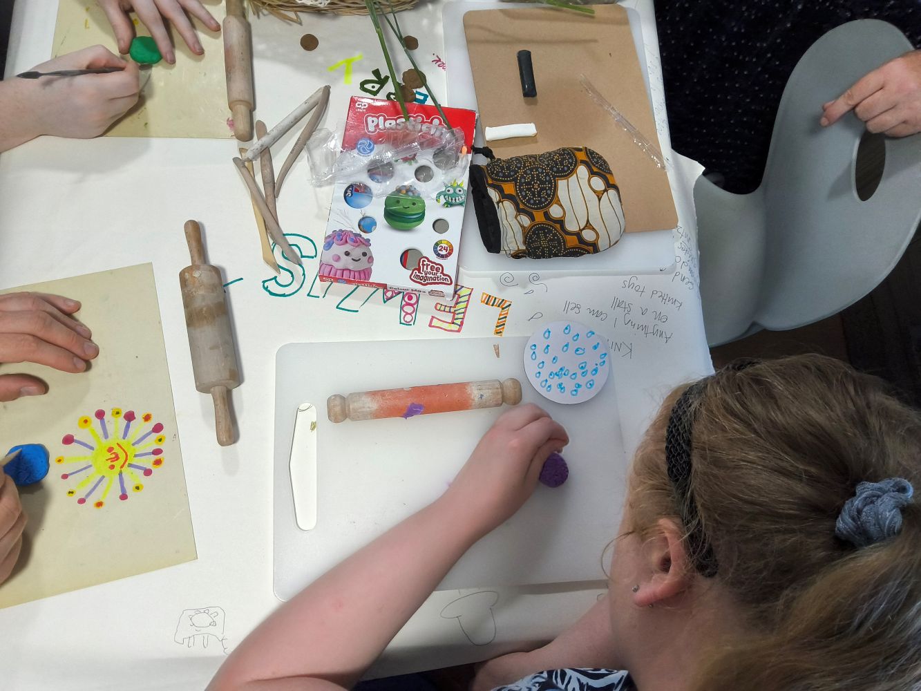 Overhead view of hands rolling, pressing and marking pieces of plasticine