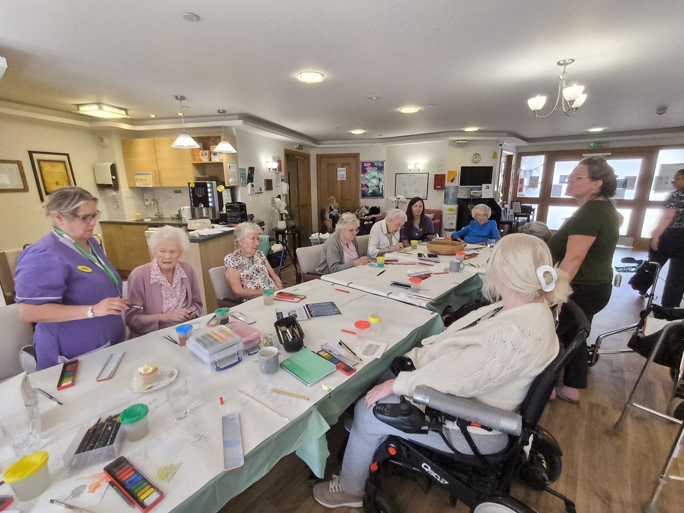 A group of adults gathered around a table covered with art materials
