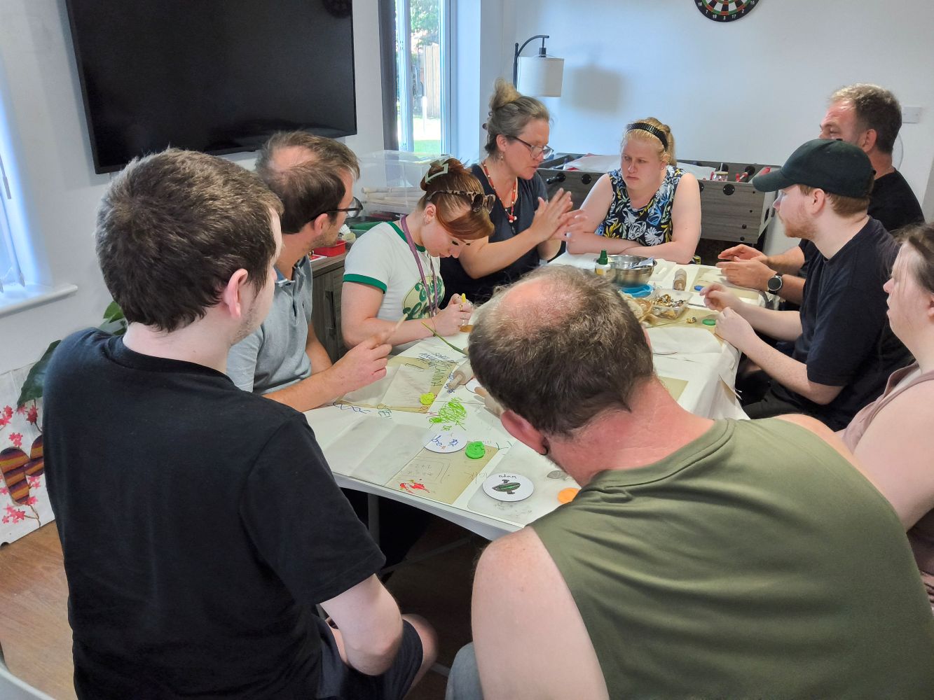 A group of people seated around a table covered in art materials