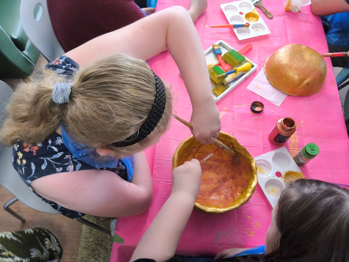 Overhead view of two people applying a bronze wash to the interior of the bowl