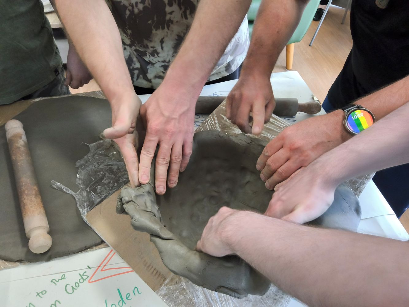 Pairs of hands smoothing out clay inside a bowl