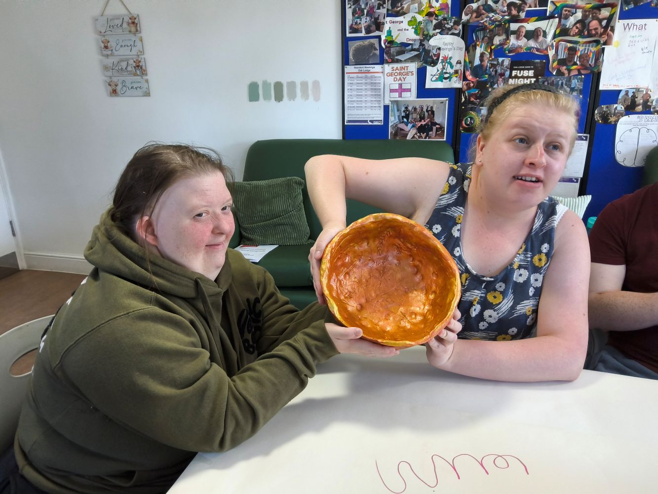 Two young women hold up their bowl to show the interior, prior to applying the gold leaf
