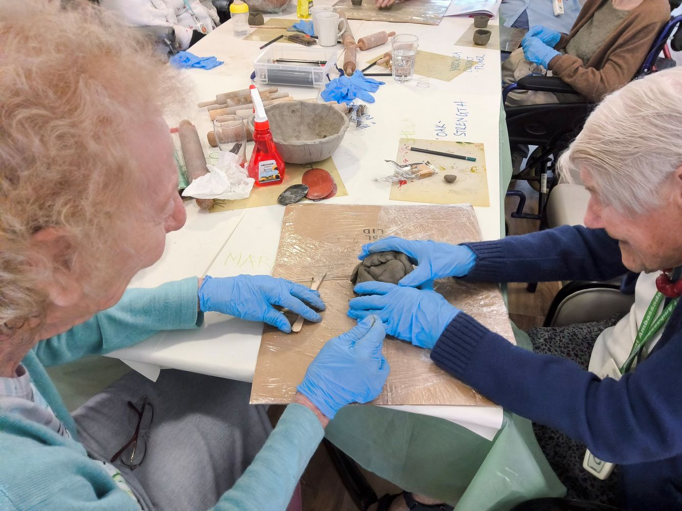 Two people working a lump of hard clay into something more manageable ble
