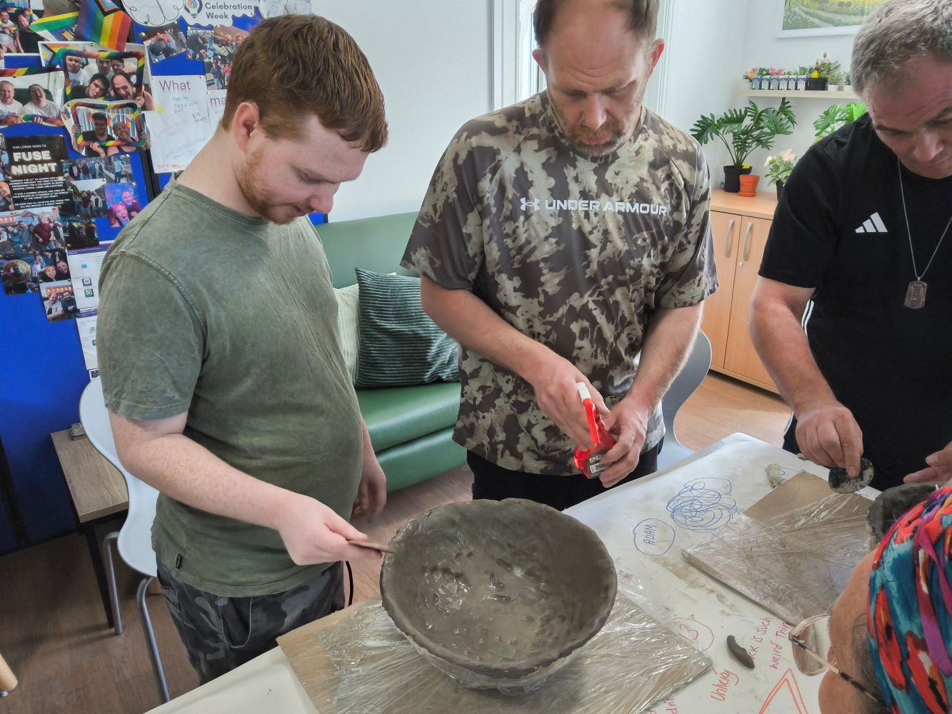 Three figures working at clay bowls