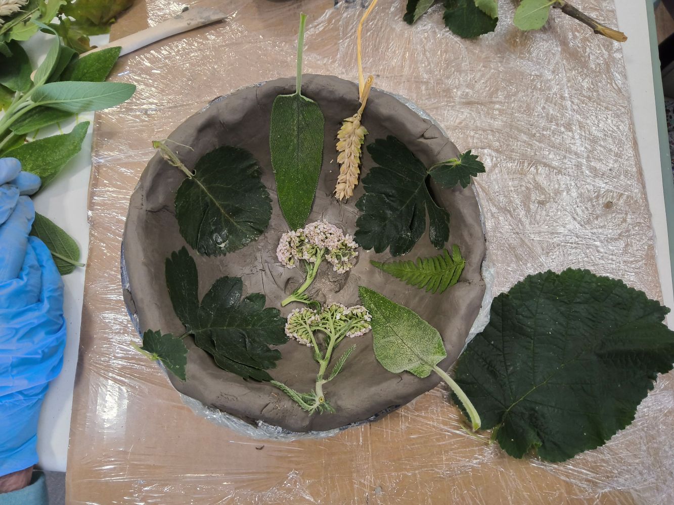 A bowl inlaid with sage, fern and other greenery