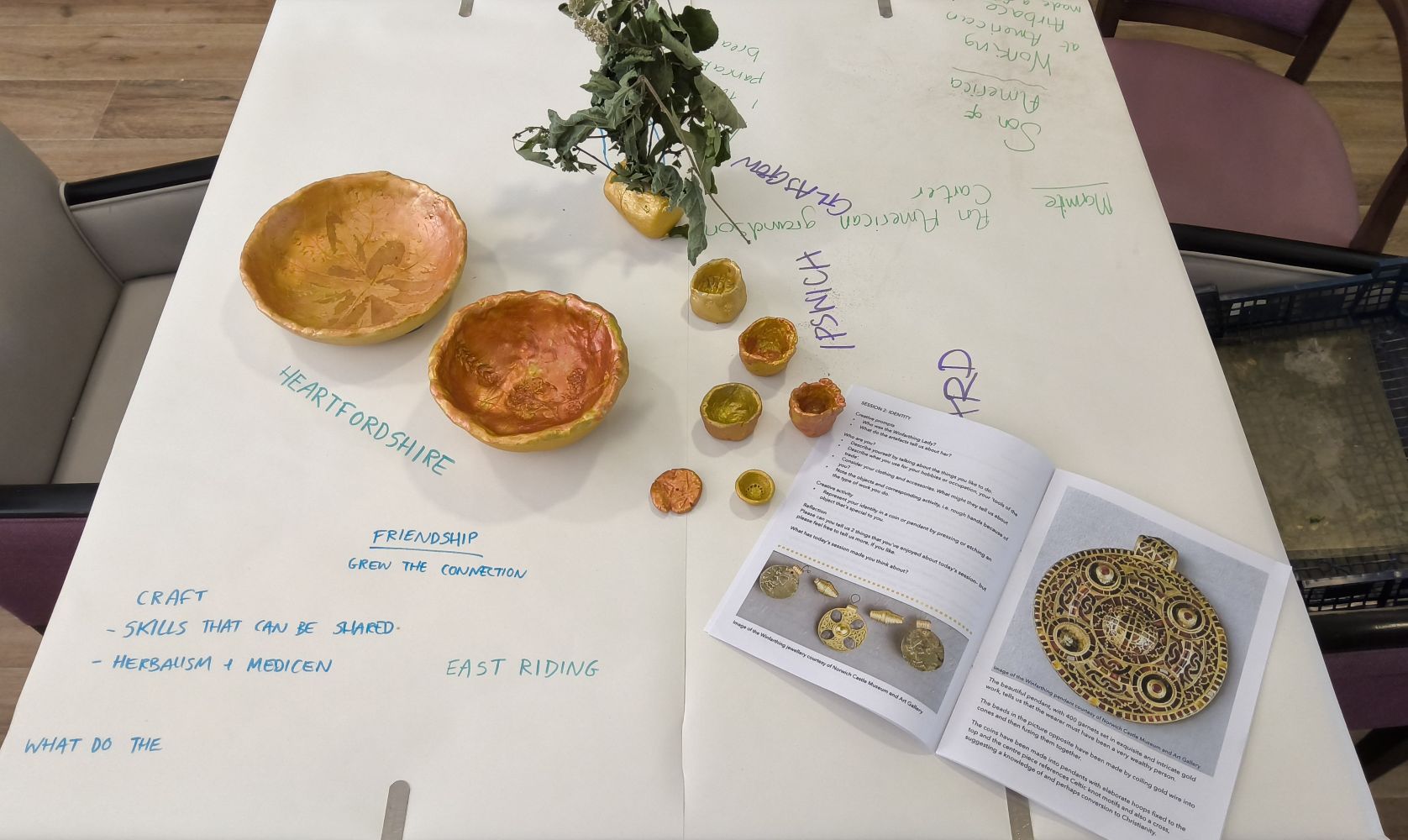 Heartfordshire. Friendship - grew the connection. Craft. Skills that can be shared. Herbalism and medicine. Also a selection of gold painted bowls and pots and a publication with an image of precious pendants and a necklace
